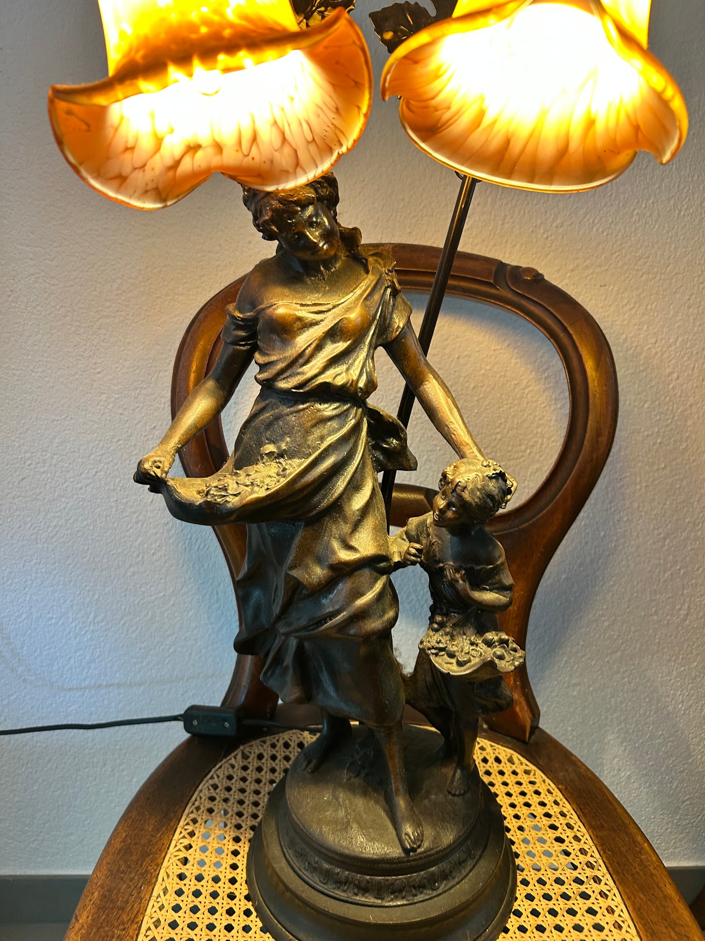 Art Nouveau lamp illuminated showing warm amber glow of original glass shades