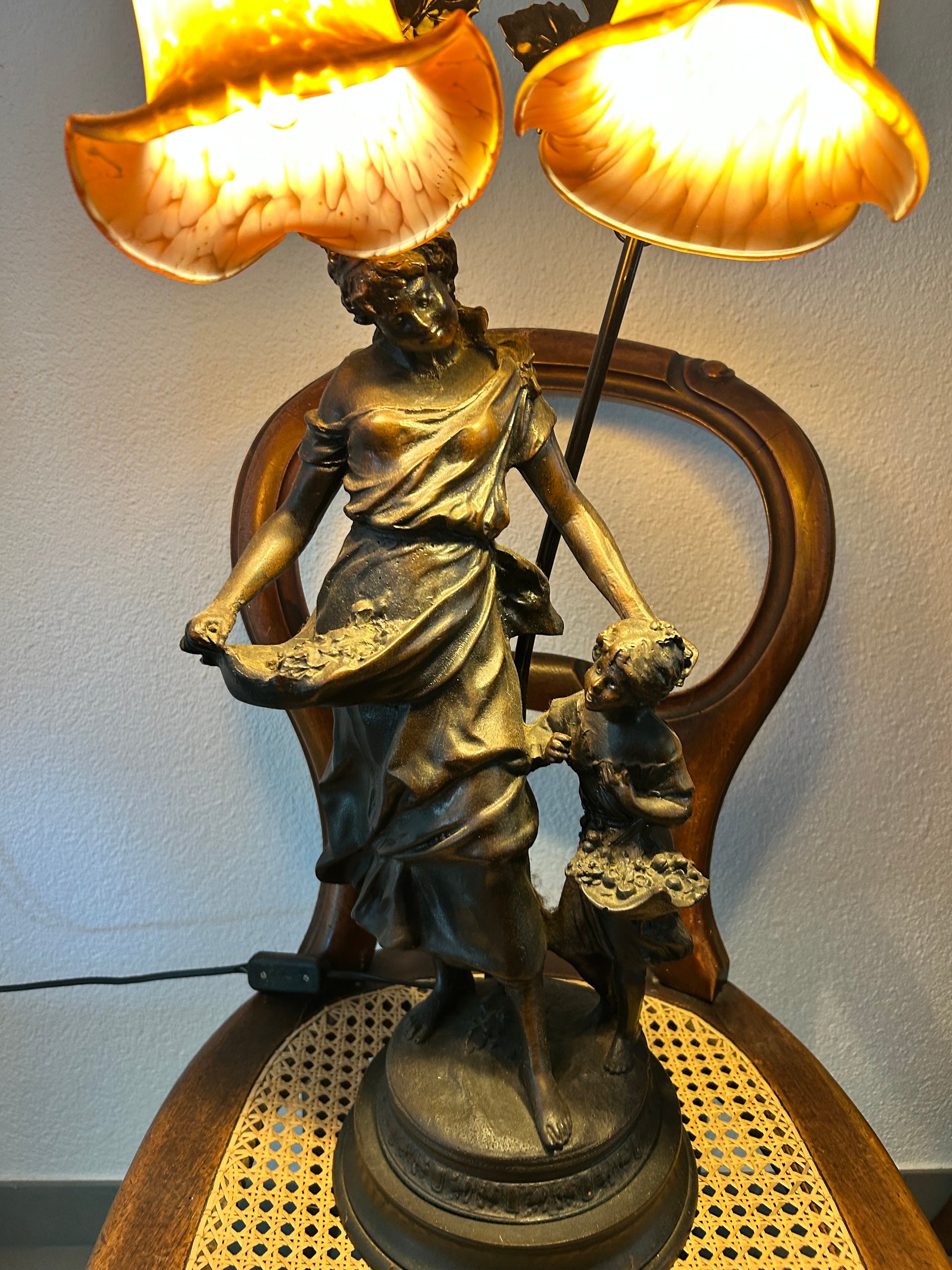 Art Nouveau lamp illuminated showing warm amber glow of original glass shades
