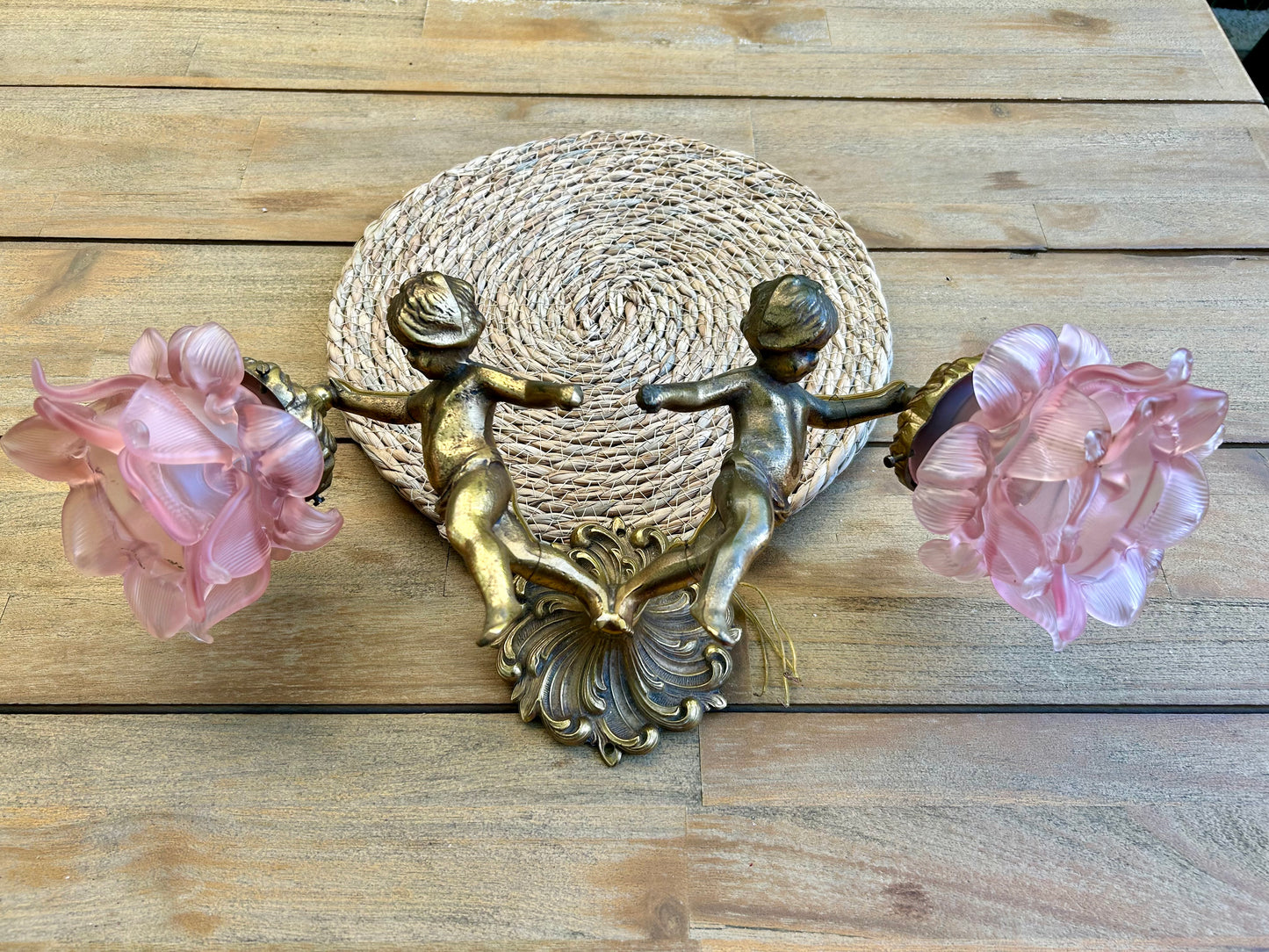 Front view of French Rococo Revival brass double cherub wall sconce with two pink peony glass shades