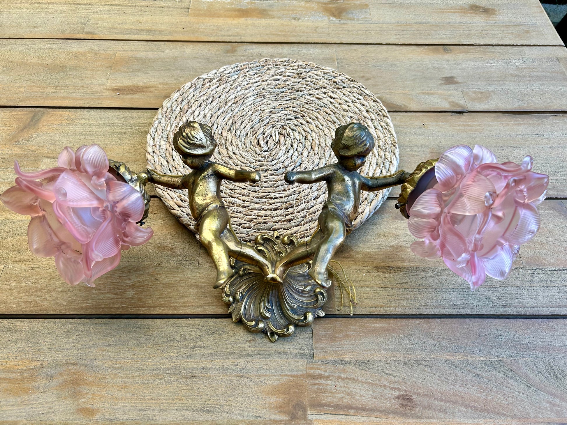 Front view of French Rococo Revival brass double cherub wall sconce with two pink peony glass shades