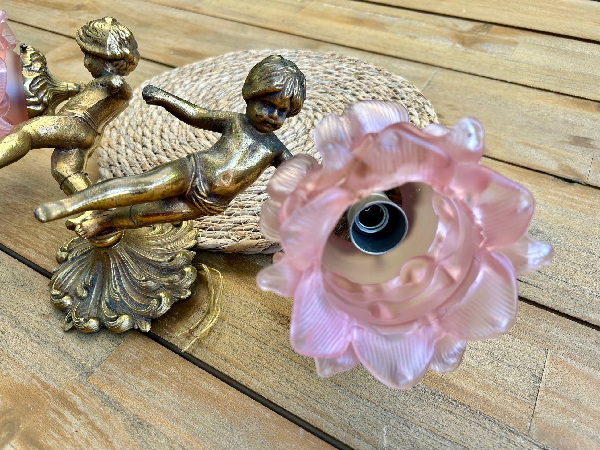 Side view of brass cherub sconce showing ornate shell base and pink peony glass shade detail