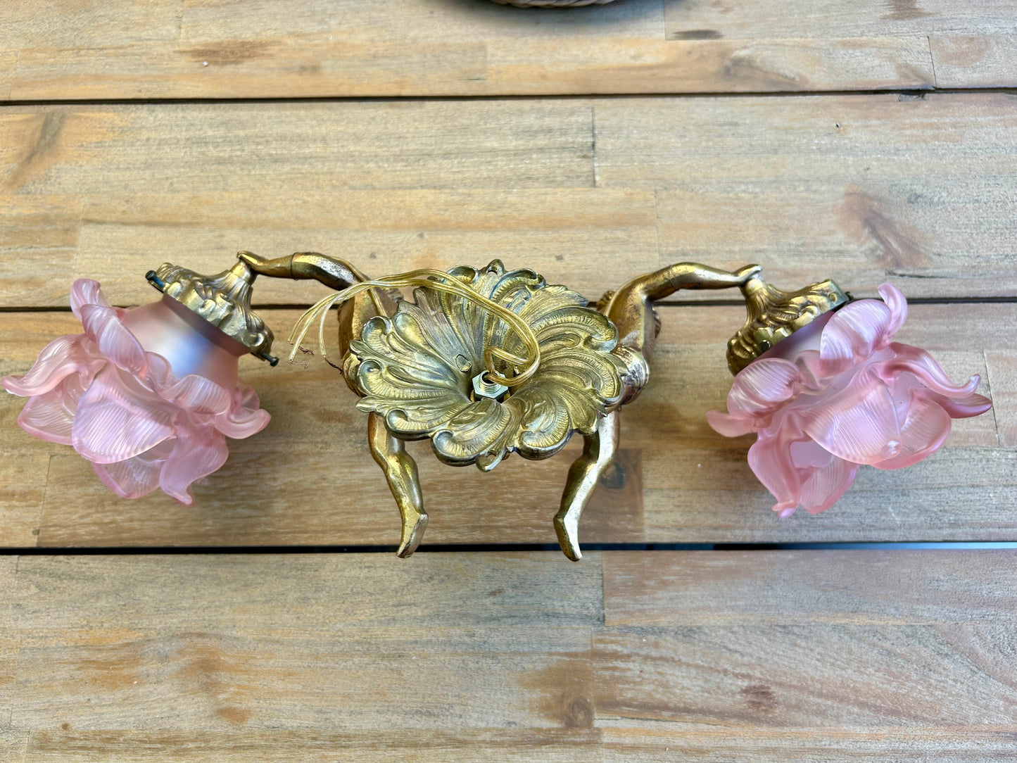 Back view of French brass cherub wall sconce showing mounting plate and ornate acanthus detail